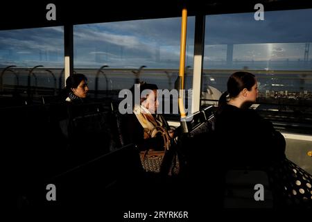 En fin d'après-midi, trois (3) femmes dans un bus traversant le Sydney Harbour Bridge, avec un aperçu de l'Opéra de Sydney en plein soleil Banque D'Images