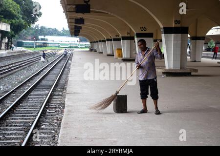 2 octobre 2023, Dhaka, Dhaka, Bangladesh : un nettoyeur balaye le sol de la gare de Kamalapur à Dhaka, Bangladesh. La gare de Kamalapur est la plaque tournante ferroviaire la plus grande et la plus animée du pays. Réputée pour sa fusion architecturale d’éléments modernes et traditionnels, cette gare emblématique a été conçue par l’architecte américain Robert Boughey et inaugurée en 1969. En tant que carrefour clé pour les lignes ferroviaires nationales et internationales, il sert de porte d'entrée essentielle à Dhaka, améliorant la connectivité et l'accessibilité de la ville tout en symbolisant le riche patrimoine ferroviaire du pays. (Crédit Imag Banque D'Images