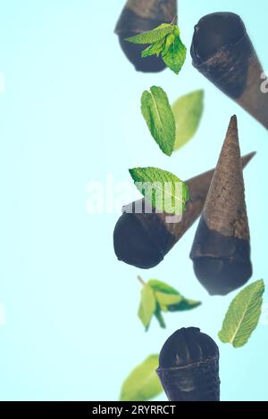 Crème glacée noire dans des cônes gaufrés sur fond pastel Banque D'Images