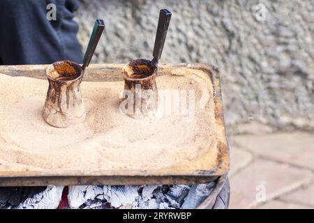 Café turc traditionnel préparé sur sable chaud.. Deux cezves remplis de café oriental chaud. Deux pots pour la préparation du café. jezveh. jezve. Banque D'Images