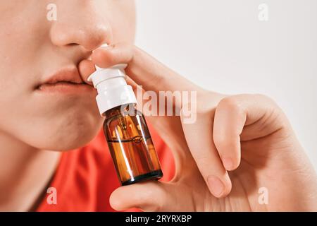 Blond Boy goutte des gouttes de nez du nez qui coule. Traitement des rhumes et rhinites allergiques. Mise au point sélective Banque D'Images