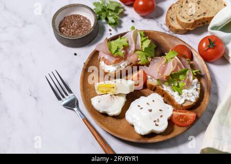 Petit déjeuner ou brunch de Pâques. Délicieux petit déjeuner ou collation - oeuf poché et fromage à la crème toast pain de seigle entier, prosciutto, Banque D'Images