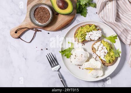 Petit déjeuner ou brunch de Pâques. Délicieux petit déjeuner ou collation - oeuf poché et fromage à la crème toast pain de seigle entier, avocat sur Banque D'Images