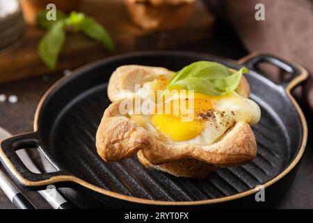 Œufs brouillés dans une pâte feuilletée avec fromage et bacon sur une assiette de pierre. Idée de petit déjeuner, encas. Banque D'Images