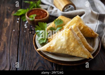 Cuisine asiatique. samsa végétarien (samosas) avec sauce tomate sur une table en bois. Populaire en Indonésie comme Risoles Sayur. Copier l'espace. Banque D'Images