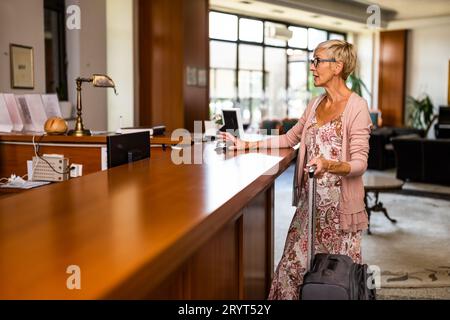 Femme mature vient à l'hôtel à la réception. Elle attend la réceptionniste. Banque D'Images