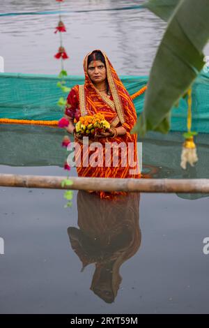 Chhath Puja, dévot féminin indien hindou exécutant des rituels de chhath puja tout en se tenant dans la rivière pour adorer le soleil du seigneur au coucher du soleil. Banque D'Images