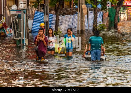 Thais pataugeait dans les eaux de crue, un père porte son fils sur ses épaules pour empêcher le jeune enfant de se mouiller. Bangkok, Thaïlande. © Kraig Lieb Banque D'Images