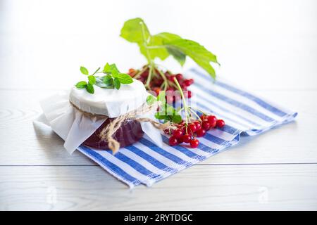 confiture de viburnum dans un bocal en verre et viburnum rouge frais sur une table en bois clair. Banque D'Images