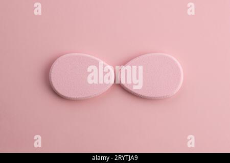 Éponge cosmétique en forme d'œuf sur fond rose. Vue de dessus Banque D'Images