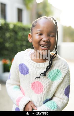 Portrait de fille afro-américaine heureuse avec des tresses debout à l'extérieur de la maison Banque D'Images