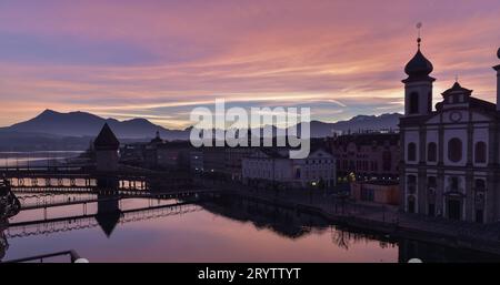 Lever du soleil le jour de Noël 2016 depuis un balcon à l'Hôtel des balances, bâtiments autour du pont de la Chapelle et teintes de lever du soleil reflétées sur la rivière Reuss Banque D'Images