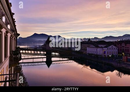 Lever du soleil le jour de Noël 2016 depuis un balcon à l'Hôtel des balances, bâtiments autour du pont de la Chapelle et teintes de lever du soleil reflétées sur la rivière Reuss Banque D'Images