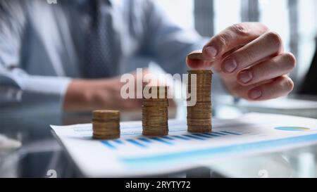 Homme d'affaires empilant des pièces sur la table, concept de croissance d'entreprise.La main place la pièce à empiler. Banque D'Images