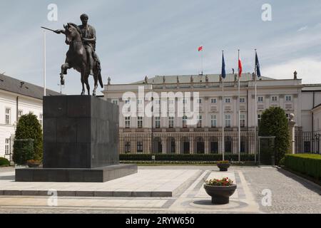 Une majestueuse statue en pierre se dresse devant un grand château entouré d'une végétation luxuriante dans le jardin Banque D'Images