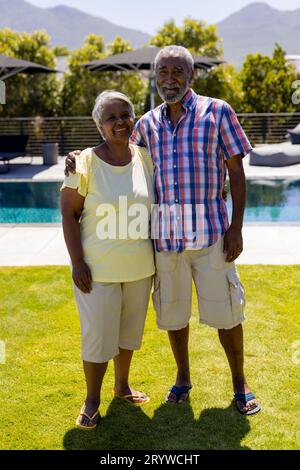 Portrait d'heureux couple biracial senior embrassant et souriant dans le jardin Banque D'Images