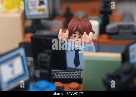 Tambov, Fédération de Russie - 30 septembre 2023 Une minifigurine d'homme d'affaires Lego effrayée assise derrière un ordinateur dans un bureau. Gros plan. Banque D'Images