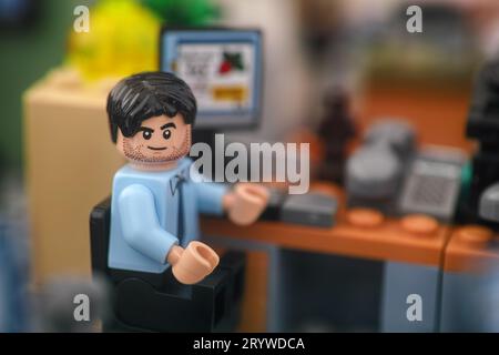 Tambov, Fédération de Russie - 30 septembre 2023 Une minifigurine d'homme d'affaires Lego assise sur une chaise derrière un ordinateur dans un bureau et regardant la caméra Banque D'Images