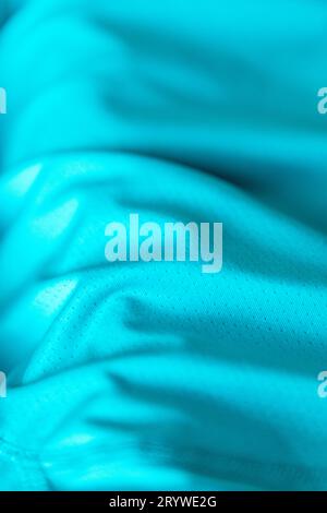 Tissu de type polyester de couleur sarcelle ou turquoise en gros plan avec lumière naturelle illuminant la texture et les plis du textile. Banque D'Images