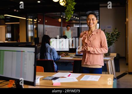 Portrait d'heureuse femme d'affaires occasionnelle biracial dans le bureau Banque D'Images