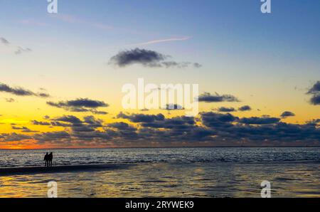 Vue sur le soleil couchant qui brille sur la mer et se reflète sur la plage, nuages avec des bords ensoleillés.Paysage Banque D'Images