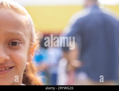 Demi-visage portrait d'écolière biracial souriante dans le terrain de jeu de l'école, espace de copie Banque D'Images