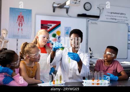 Enseignant féminin diversifié et écoliers faisant une expérience en classe de chimie Banque D'Images