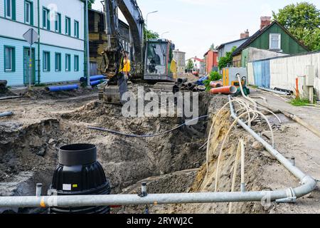 Vue de reconstruction de rue, tranchée profonde, système d'assèchement, nouveaux et anciens tuyaux, puits en plastique, excavatrice, remplacement de pipeline Banque D'Images