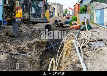 Vue de reconstruction de rue, tranchée profonde, système d'assèchement, nouveaux et anciens tuyaux, puits en plastique, excavatrice, remplacement de pipeline Banque D'Images