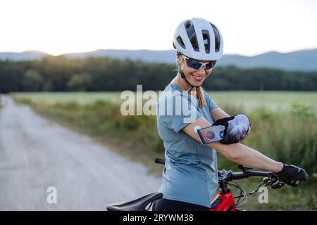 Cycliste diabétique connectant un moniteur de glycémie continu à son smartphone pour surveiller son taux de sucre dans le sang en temps réel. Banque D'Images