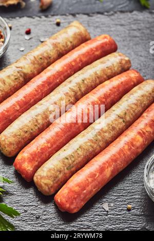 Bouchers crus saucisses sur ardoise avec herbes.Vue de dessus Banque D'Images
