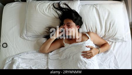 Femme se réveillant le matin couché dans le lit, vue de dessus perspective Banque D'Images