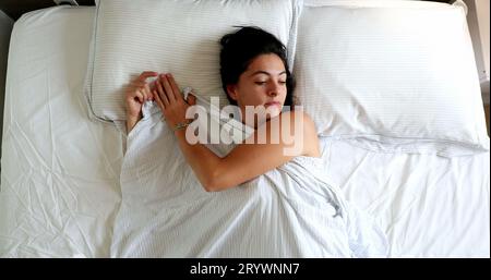 Femme se réveillant le matin couché dans le lit, vue de dessus perspective Banque D'Images