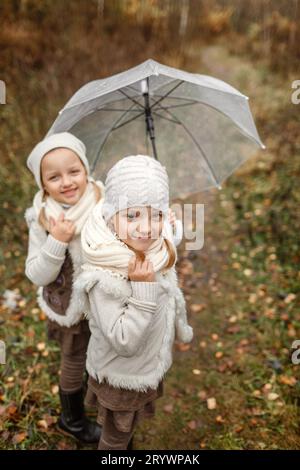 Portrait de jeunes filles jumelles avec un parapluie dans le parc. Cadre vertical. Vue d'en haut. La fille au premier plan est nette, la fille à l'intérieur Banque D'Images