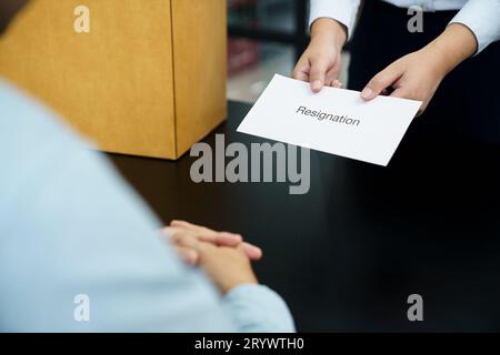 Femme d'affaires envoyant la lettre de démission au patron et tenant des trucs démissionner dépriment ou portant la boîte en carton par le bureau dans le bureau Banque D'Images