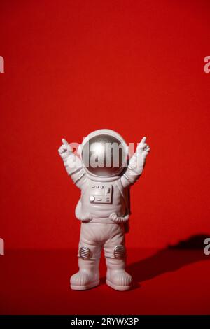 Astronaute jouet en plastique sur fond rouge coloré Copier l'espace. Concept de voyage hors de la terre, vols commerciaux privés d'homme spatial Banque D'Images