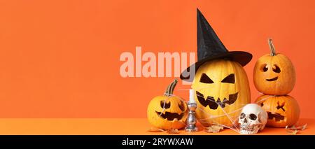 Citrouilles d'Halloween sculptées, bougie et crâne sur fond orange avec espace pour le texte Banque D'Images