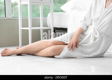 Femme pieds nus assise sur le sol avec chauffage dans la chambre Banque D'Images