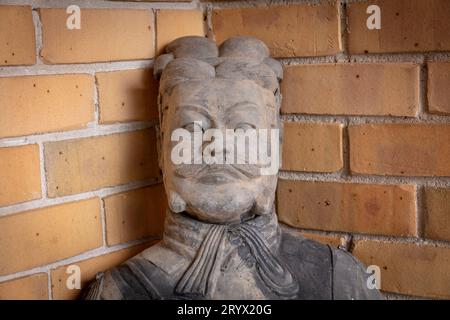 Photographie du visage et de la tête d'une imitation statue de soldat en terre cuite contre un mur de briques brunes dans une habitation urbaine Banque D'Images