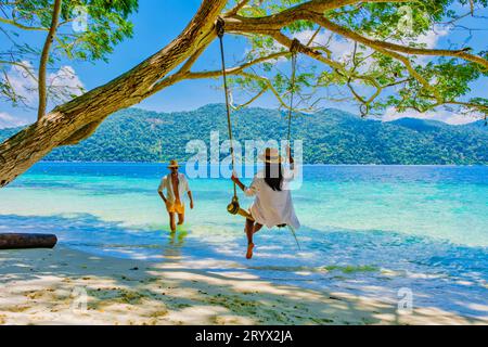 Un couple d'hommes et de femmes sont sur la plage avec une balançoire à corde Banque D'Images