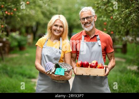 Concept d'éco-agriculture. Conjoints aînés souriants posant dans leur propre verger Banque D'Images