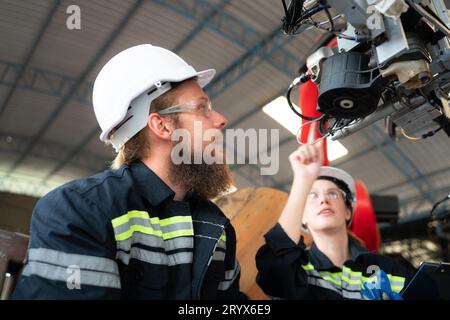 Ingénieur électricien avec la mission d'installer un système électrique de bras robotisé Banque D'Images