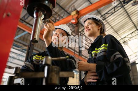 Les deux ingénieurs mécaniques vérifient l'état de fonctionnement de la nouvelle machine après avoir terminé l'installation Banque D'Images