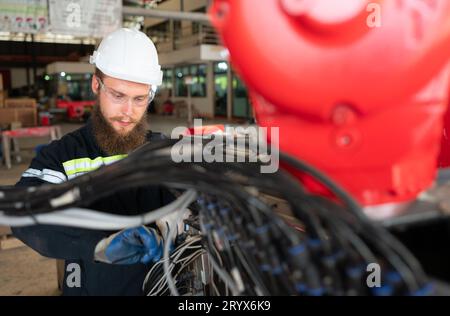 Ingénieur électricien avec la mission d'installer un système électrique de bras robotisé Banque D'Images