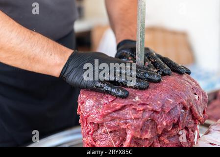 Le maître prépare du kebab turc à cuire à partir de viande rouge, de viande de doner kebab non cuite, de gyros grecs à la broche dans un restaurant . Photo de haute qualité Banque D'Images