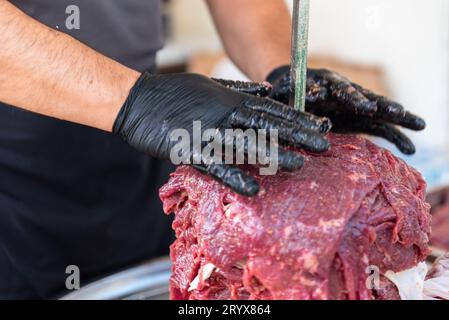 Le maître prépare du kebab turc à cuire à partir de viande rouge, de viande de doner kebab non cuite, de gyros grecs à la broche dans un restaurant . Photo de haute qualité Banque D'Images