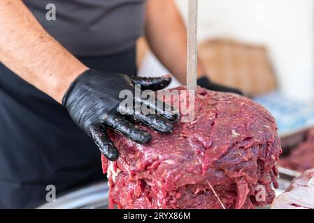 Le maître prépare du kebab turc à cuire à partir de viande rouge, de viande de doner kebab non cuite, de gyros grecs à la broche dans un restaurant . Photo de haute qualité Banque D'Images