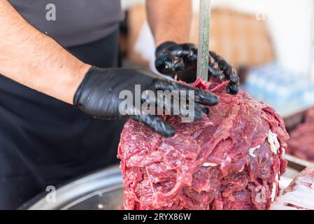 Le maître prépare du kebab turc à cuire à partir de viande rouge, de viande de doner kebab non cuite, de gyros grecs à la broche dans un restaurant . Photo de haute qualité Banque D'Images