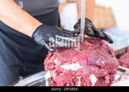 Le maître prépare du kebab turc à cuire à partir de viande rouge, de viande de doner kebab non cuite, de gyros grecs à la broche dans un restaurant . Photo de haute qualité Banque D'Images