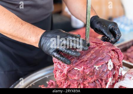 Le maître prépare du kebab turc à cuire à partir de viande rouge, de viande de doner kebab non cuite, de gyros grecs à la broche dans un restaurant . Photo de haute qualité Banque D'Images